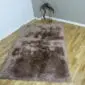 Rectangular sheepskin rug in mottled brown and grey tones with a thick, textured pile.