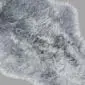 A double steel grey sheepskin rug with long, thick wool and a natural curved shape.