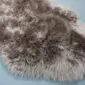 Close-up of a Paco sheepskin rug featuring long, textured wool in mottled shades of grey, brown, and cream.