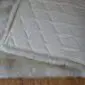 Close-up of a stone grey sheepskin rug showing the thick wool pile and the quilted non-slip backing.