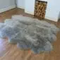 Large grey sheepskin rug with a thick, fluffy texture and natural scalloped edges on a wooden floor.