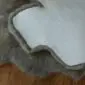 Close-up of a grey sheepskin rug showing the thick wool pile and the white leather underside.