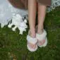 Beige flip-flop slippers with thick wool straps and footbeds worn on feet.