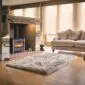 Rectangular stone grey sheepskin rug with a thick, textured pile on a wooden floor.
