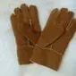 A pair of children's tan suede sheepskin gloves with visible stitching and cream wool lining at the cuffs.