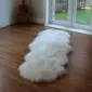 UKDouble Long, ivory white double sheepskin rug with a thick, fluffy texture laid on a wooden floor.
