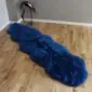Long navy blue double sheepskin rug with a thick, textured wool pile on a wooden floor.