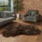 Hide Rugs_Lifestyle_0045 Large, dark brown and grey mottled rare breed sheepskin rug with a natural, irregular shape on a wooden floor.