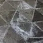 Close up of a patchwork cowhide rug featuring dark grey and black triangular panels with natural hair textures.