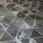 Close-up of a patchwork cowhide rug featuring dark grey and black triangular panels in a geometric pyramid pattern.