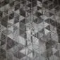 Patchwork cowhide rug featuring a geometric pyramid pattern in shades of black, grey, and charcoal.