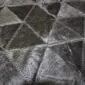 Close up of a patchwork cowhide rug featuring dark grey and black triangular panels with visible stitching.