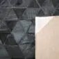 Black patchwork cowhide rug with a geometric triangle pattern and a tan leather backing.
