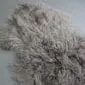 Long, curly vole grey Mongolian lambskin wool rug with a textured, shaggy appearance.