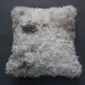 Square Tibetan sheepskin cushion with long, curly grey and brown wool.
