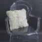 Square white Tibetan sheepskin cushion with long curly wool, resting on a acrylic .