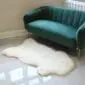 Large cream-coloured natural sheepskin rug with an irregular organic shape on a tiled floor.