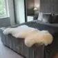 Large cream-coloured natural sheepskin rug with thick wool and an irregular organic shape.
