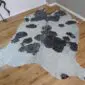Natural shaped cowhide rug with black spots on a white and metallic silver speckled background.