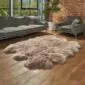 Hide Rugs_Lifestyle_0322 Large taupe sheepskin rug with a thick, fluffy texture and irregular natural edges on a wooden floor.