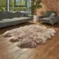 Hide Rugs_Lifestyle_0322 Large taupe sexto sheepskin rug with a thick, fluffy texture and natural scalloped edges on a wooden floor.
