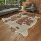 Natural shaped cowhide rug with brown and white patches and rose gold metallic speckles on a wooden floor.