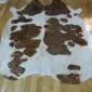 Natural white cowhide rug with large brown patches and rose gold metallic speckles.