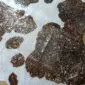 Natural brown and white cowhide rug with metallic rose gold splatters and a textured finish.