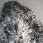 Close-up of a curly sheepskin rug with natural grey and white wool textures.