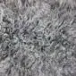Close up of a natural grey sheepskin rug with thick, curly wool fibres.