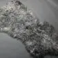 Natural grey sheepskin rug with a thick, curly wool texture and an irregular organic shape.