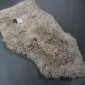 Beige curly sheepskin rug with a natural organic shape and thick textured wool pile.