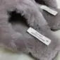 Close-up of mink-coloured sheepskin slippers with fluffy cross-over straps and white brand labels.