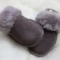A pair of mink-coloured sheepskin slippers with suede uppers and fluffy fur collars.