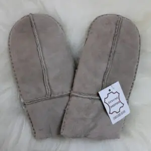A pair of beige sheepskin mittens with visible stitching and a white product tag.