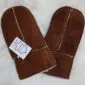 A pair of brown suede kids' sheepskin mittens with visible cream wool lining and stitched seams.