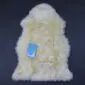 IMG_8327 Cream-coloured, thick-pile lambskin rug with a natural pelt shape and a blue product tag.