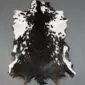 Natural goatskin rug with a mottled black and white pattern and irregular edges.