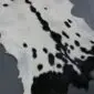 Natural goatskin rug with white fur and black spotted markings.