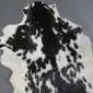Natural goatskin rug with a speckled black and white pattern and irregular edges.