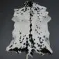 Natural goatskin rug with white fur and black spots, featuring a dark stripe down the centre.