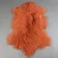 Burnt orange Mongolian lambskin rug with long, curly wool fibres and a natural hide shape.