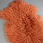 Burnt orange Mongolian lambskin rug with long, curly wool fibres and an irregular natural shape.