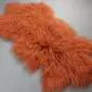 Burnt orange Mongolian lambskin rug with long, curly wool fibres and a natural hide shape. detail view
