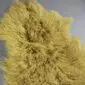 Mustard yellow Mongolian lambskin rug with long, curly wool fibres.