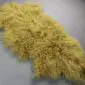 Mustard yellow Mongolian lambskin rug with long, curly wool fibres and an irregular natural shape.