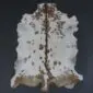 Natural goatskin rug with white fur, brown spots, and a dark brown stripe down the centre.
