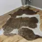 Natural shaped cowhide rug with brown and white patches and gold metallic speckled details.