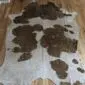Natural shaped cowhide rug with white fur and large brown spots featuring gold metallic speckles.