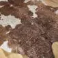Brown and White Gold Metallic Cowhide Rug CM283 (5) Close-up of a brown and white cowhide rug with metallic rose gold speckles.